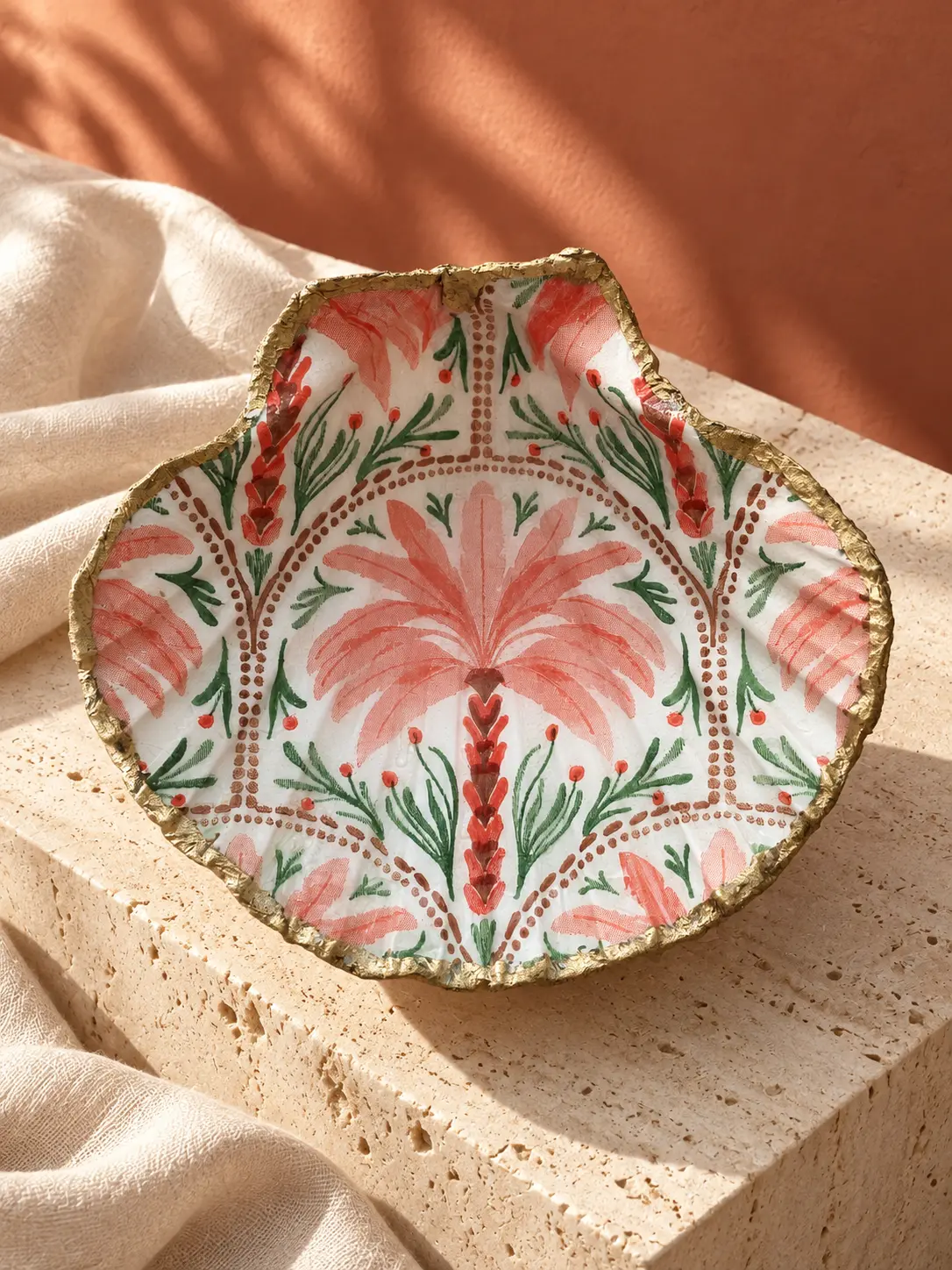 Coquille Saint-Jacques ornée d'un motif de palmiers corail et vert, bordure dorée.