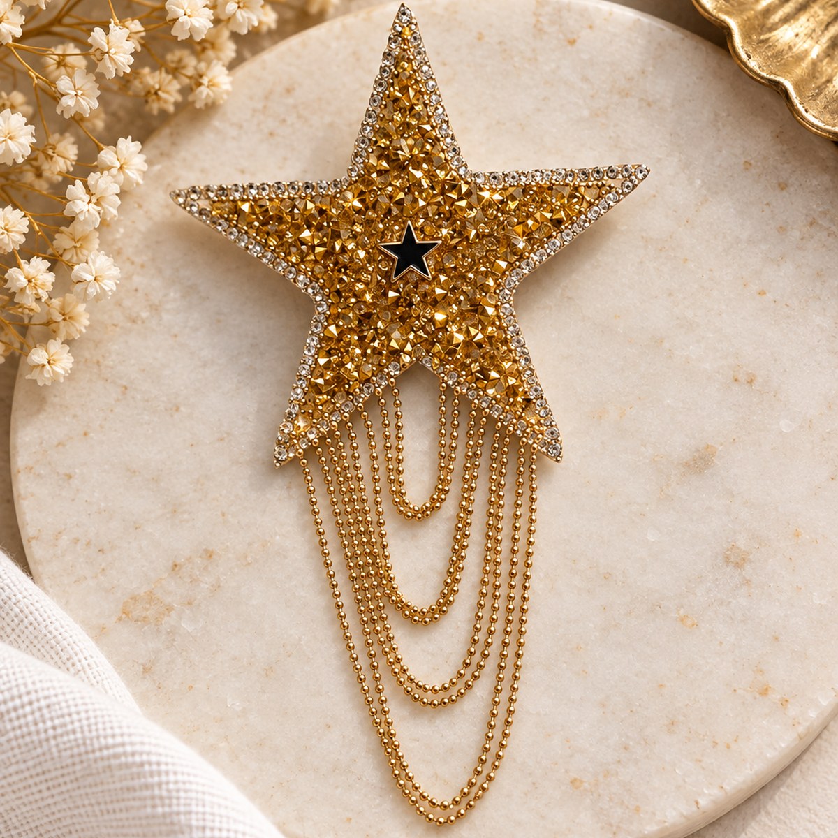 Broche étoile sertie de strass dorés, prolongée de fines chaînes à billes